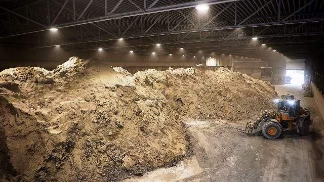 Zinc ash stockpiled under cover, with a loader working the heaps